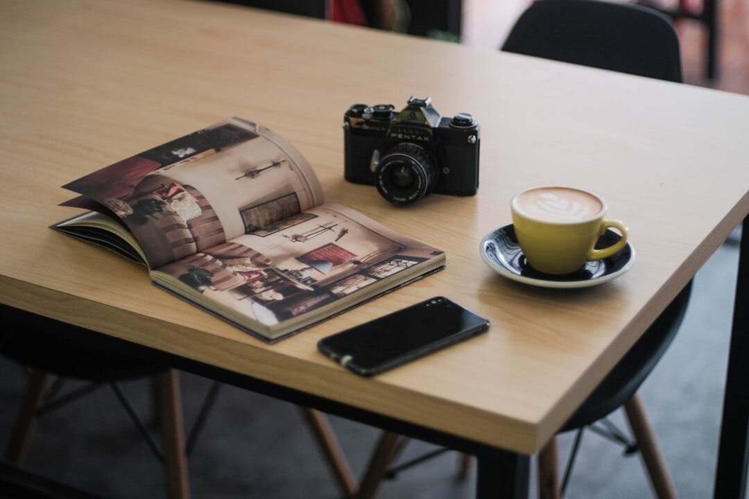 Close view of a professional camera and lens resting on a cafe table during a commercial shoot